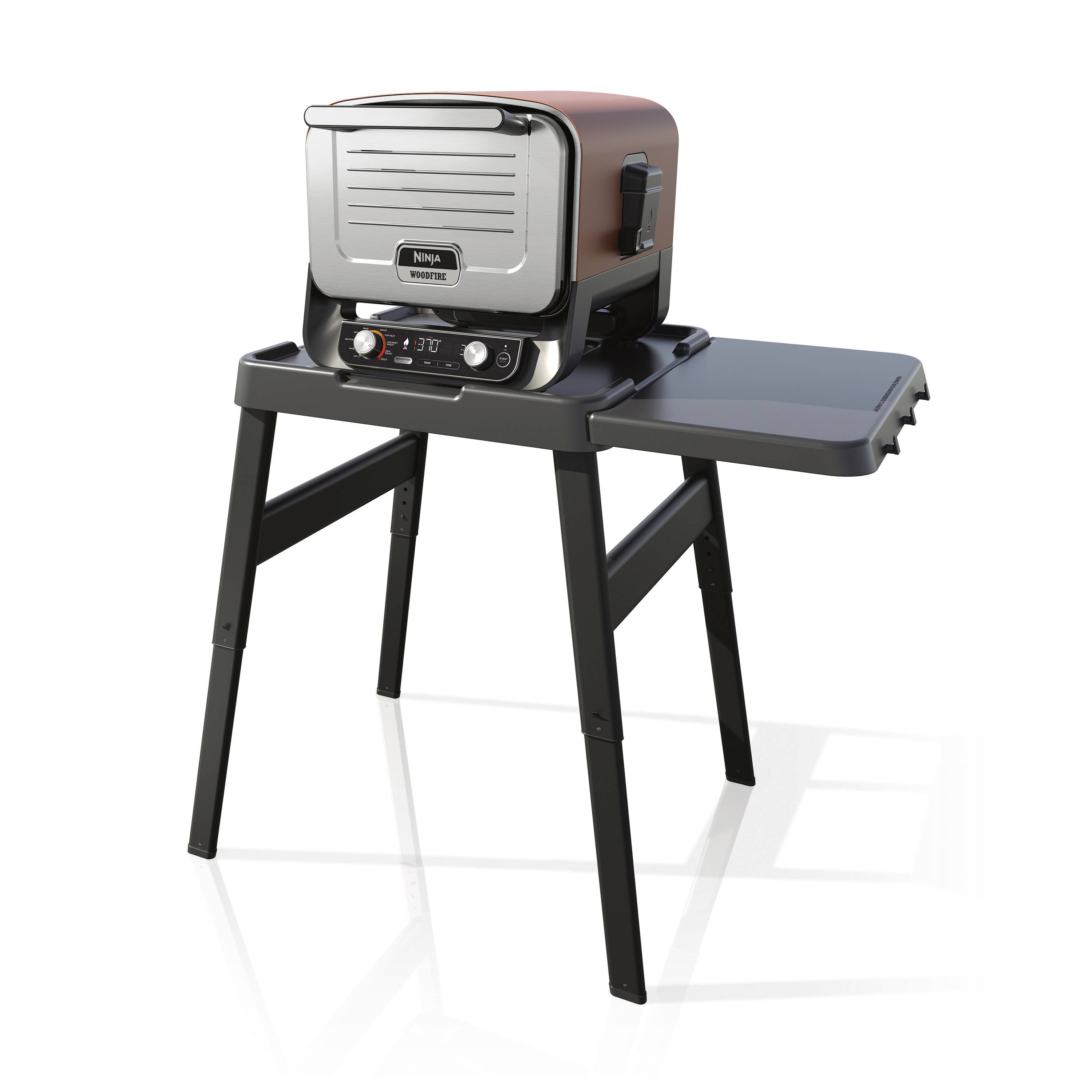 Un grill portable avec un couvercle rouge sur un support, équipé d'une tablette latérale. Adapté pour la cuisine en extérieur.