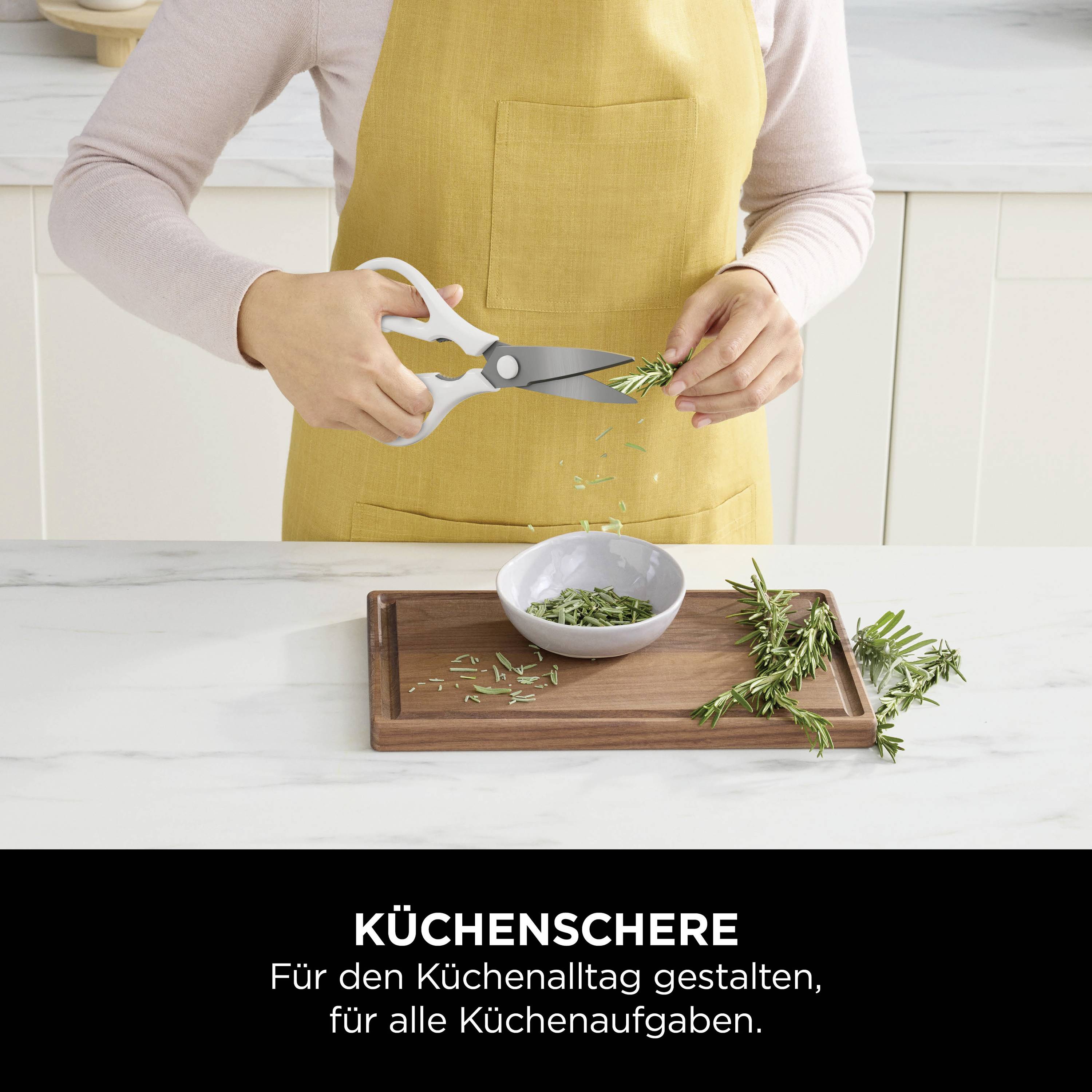 Une personne coupe des herbes sur une planche à découper en bois avec des ciseaux de cuisine. Texte : 'Ciseaux de cuisine - Conçus pour le quotidien culinaire.'