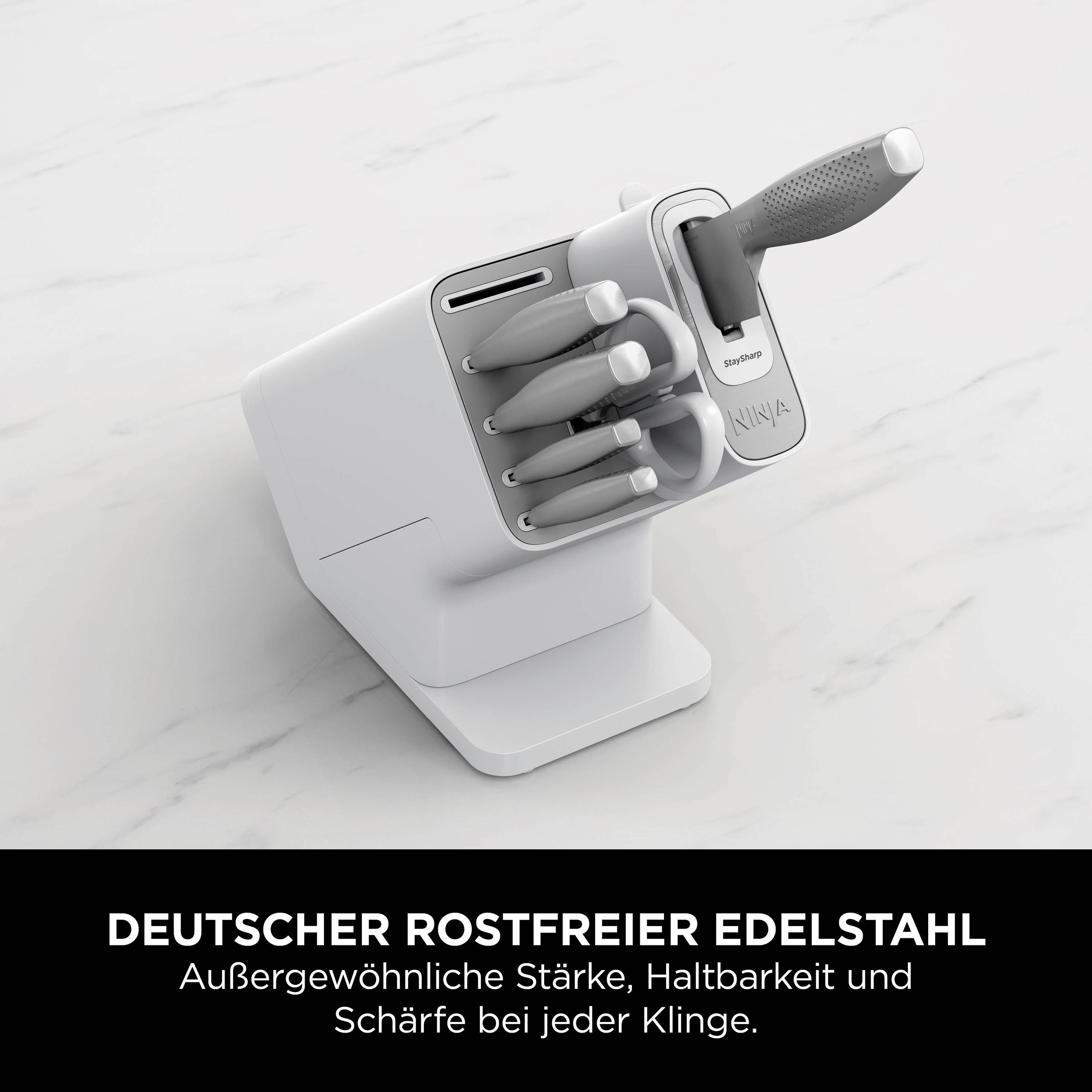 Un bloc de couteaux blanc contenant plusieurs couteaux. Texte en dessous : 'Acier inoxydable allemand. Force, durabilité et tranchant exceptionnels pour chaque lame.'