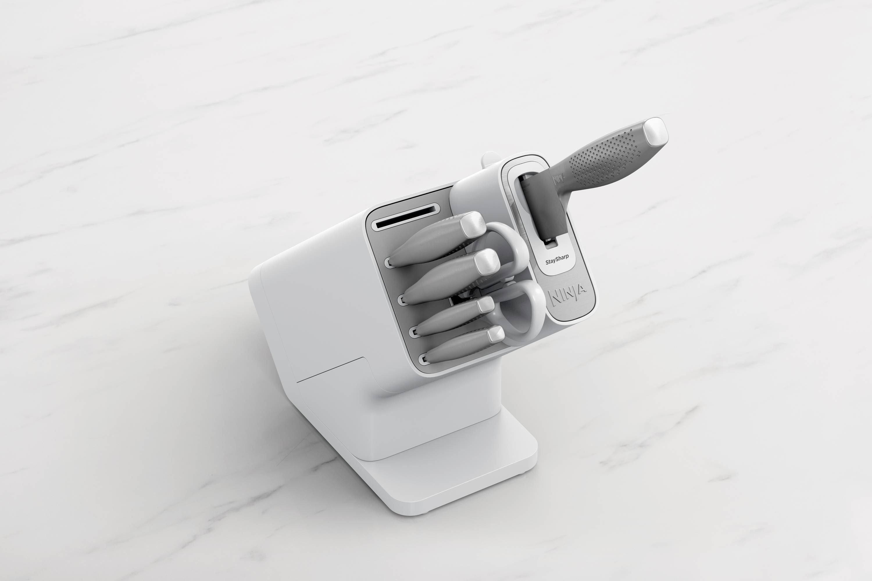 Un bloc de couteaux avec cinq couteaux insérés et un aiguiseur intégré, placé sur une surface de cuisine en marbre blanc.