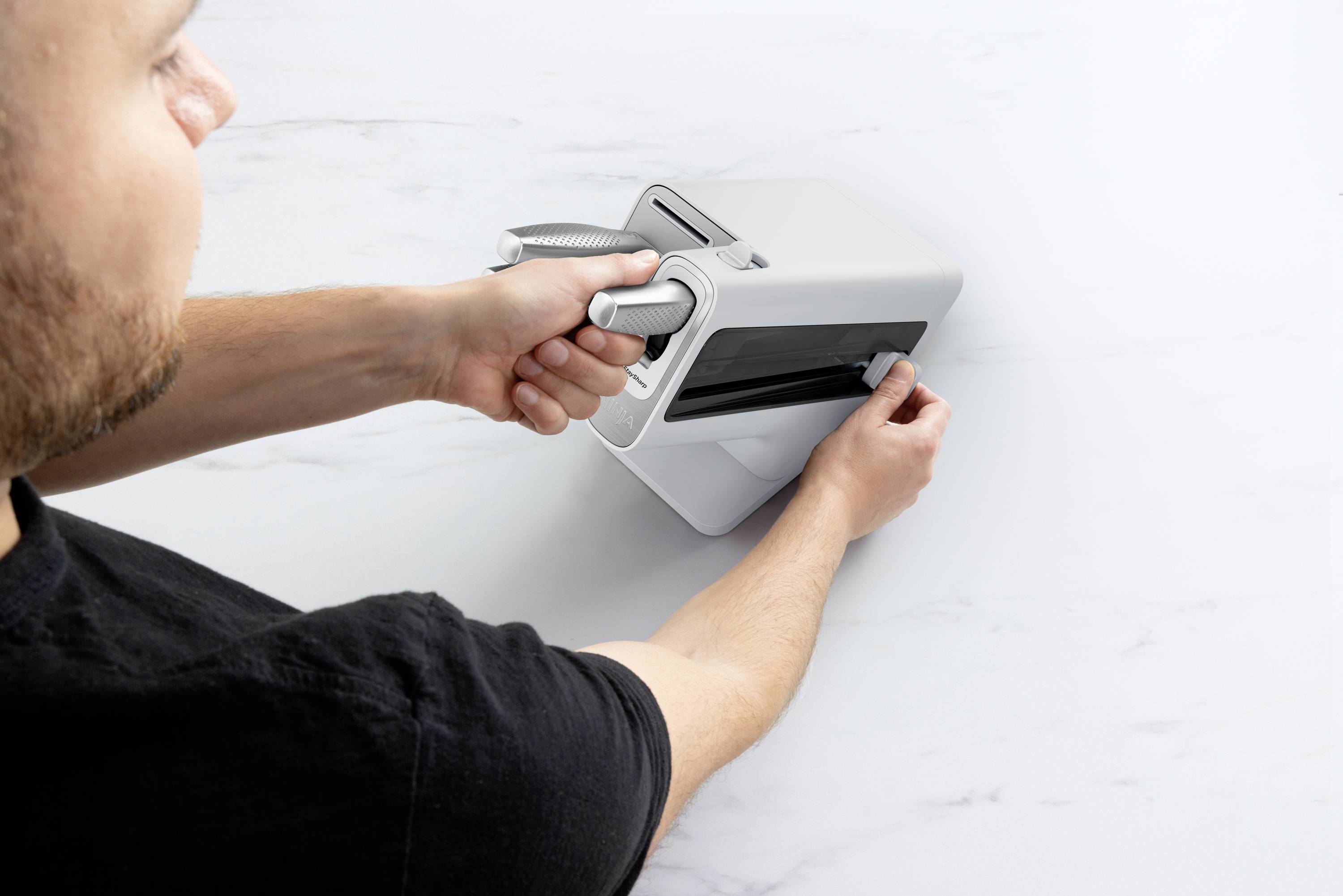 Une personne tourne un levier sur un appareil moderne et blanc posé sur une surface claire.