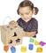 Un enfant joue avec un puzzle en bois. Il trie des formes géométriques colorées dans les ouvertures correspondantes d'un cube en bois.