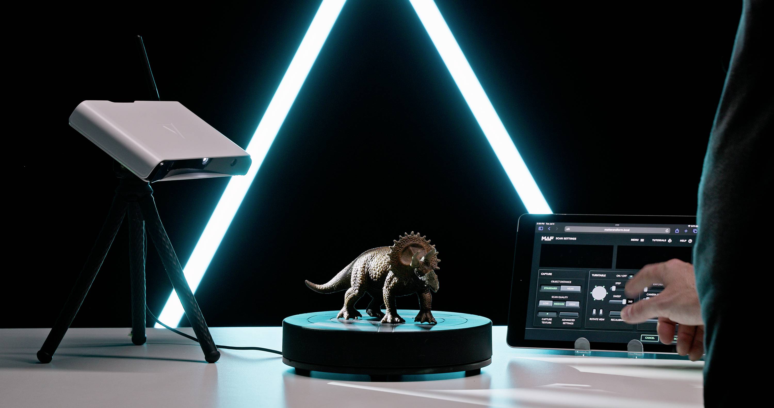 Un modèle de dinosaure tourne sur un socle, une tablette affiche des options de contrôle, des barres lumineuses bleues brillent en arrière-plan.