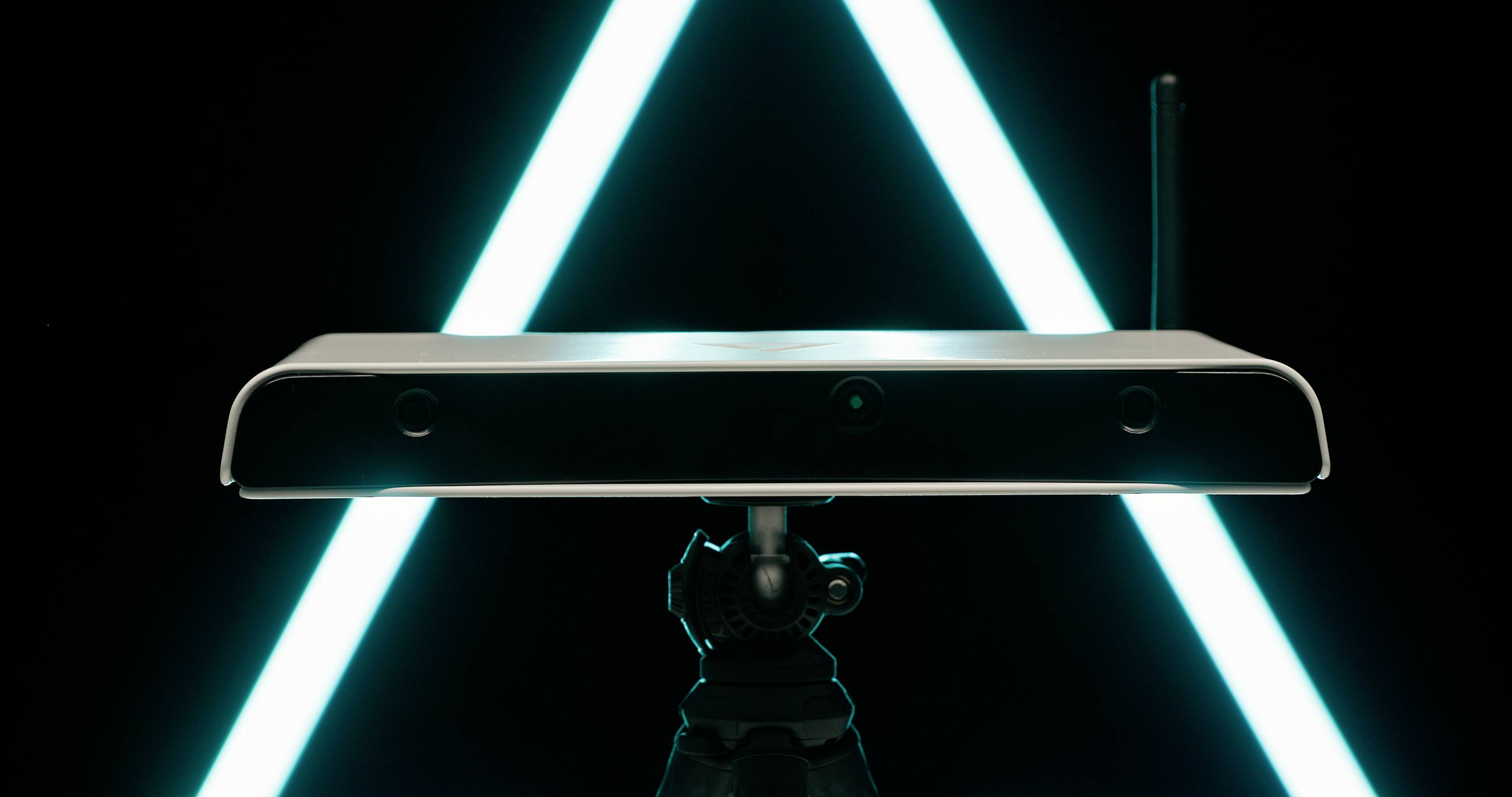 Un appareil rectangulaire équipé de caméras sur un trépied, devant une lumière triangulaire bleu vif, symbolisant une technologie tournée vers l'obscurité.