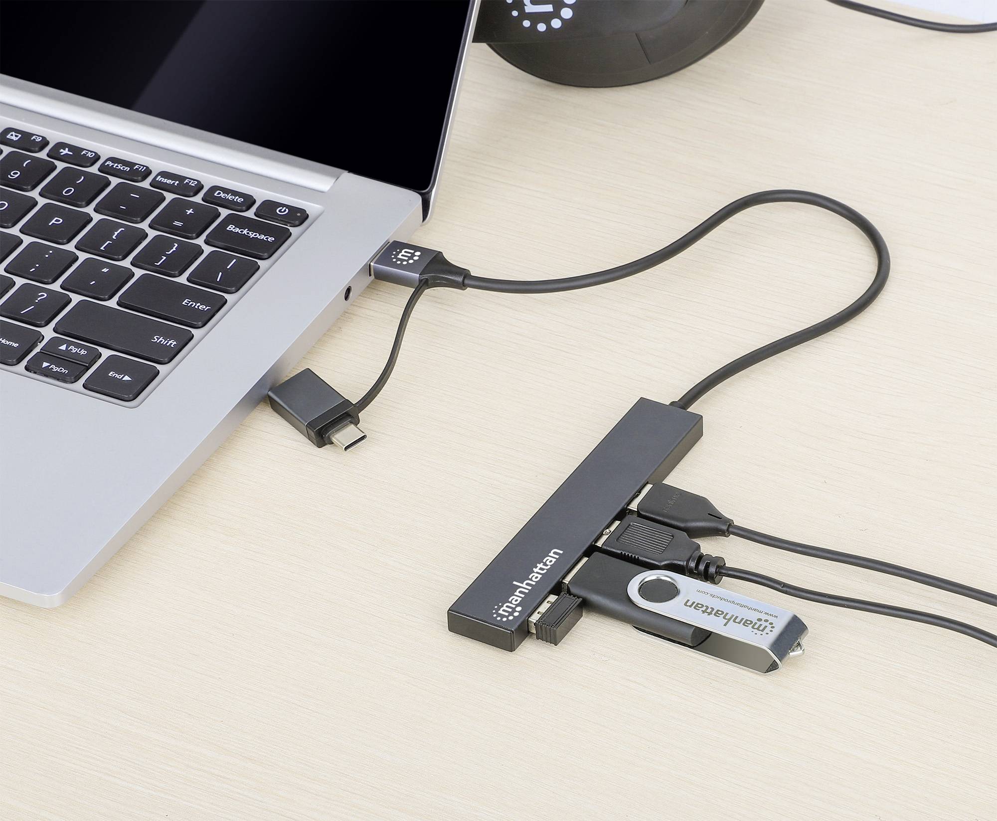 Un ordinateur portable est connecté à plusieurs appareils via un hub USB, notamment une clé USB et un lecteur de cartes.