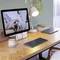 Un bureau avec un moniteur affichant un chat sur un canapé. À côté se trouvent une lampe, une tasse, un clavier et un cahier.