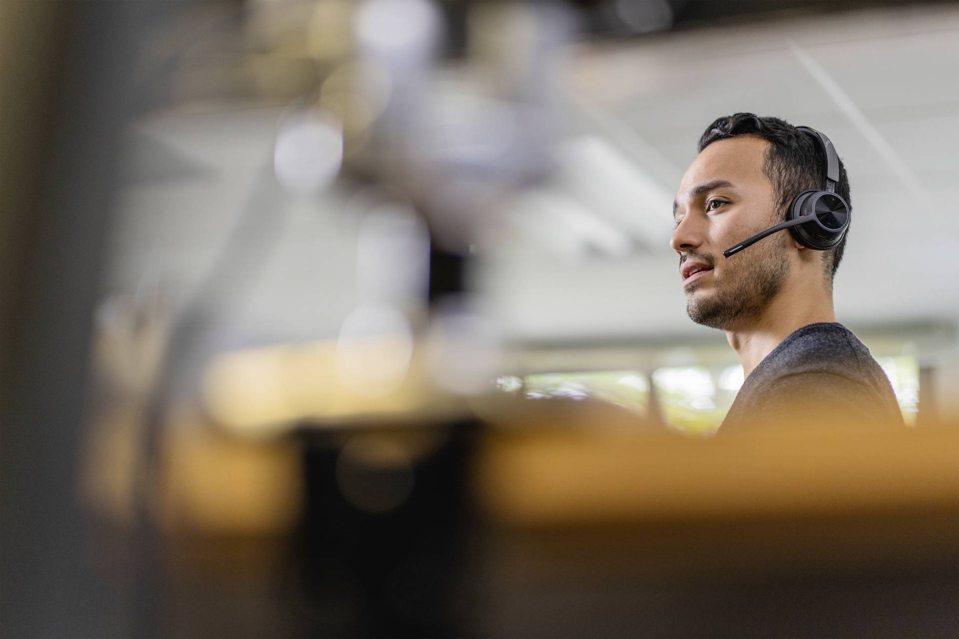 Un homme à l'apparence professionnelle portant un casque travaille dans un bureau moderne, probablement dans un service client ou un rôle de support technique.