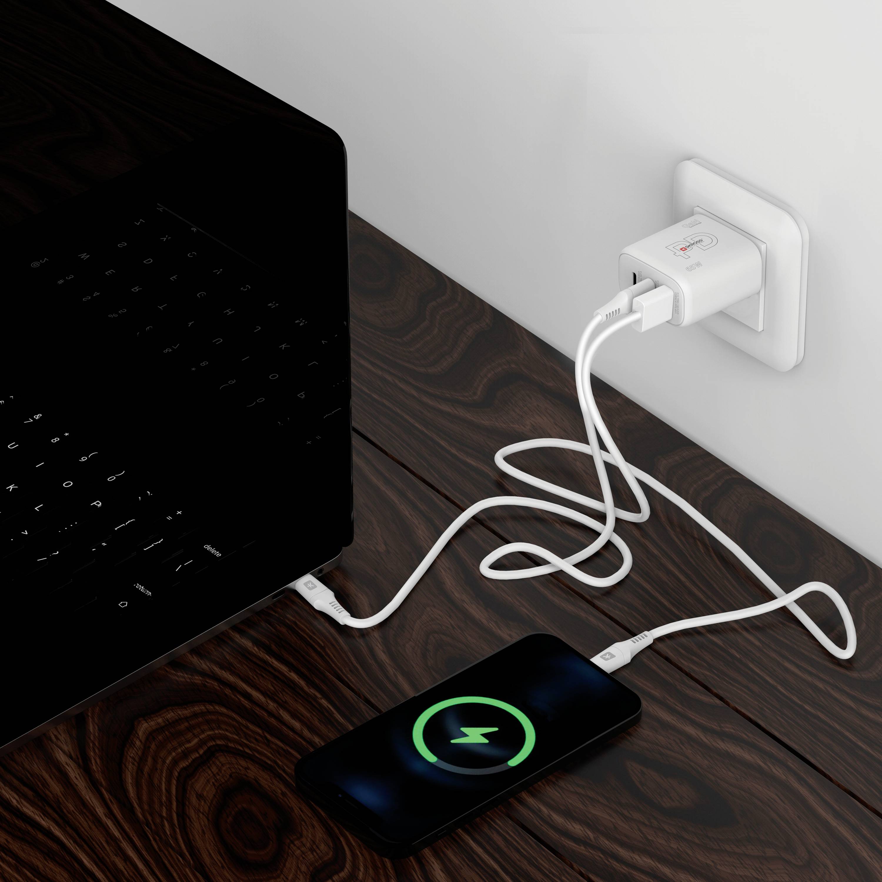 Un smartphone est en train de charger branché à un chargeur dans une prise électrique. L'écran affiche un symbole de charge.