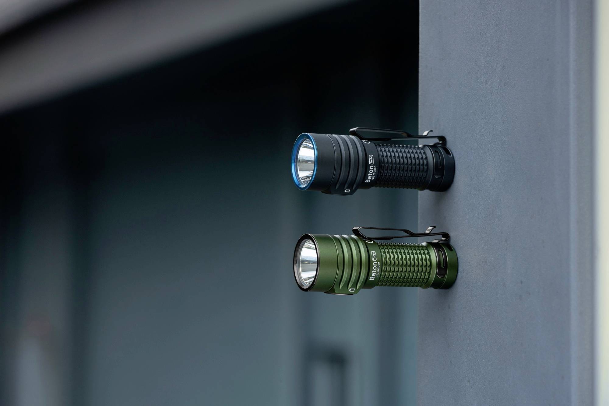 Deux lampes de poche, l'une noire et l'autre verte, fixées horizontalement sur une surface métallique grise ; toutes deux munies d'une poignée texturée.