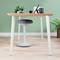 Bureau avec plateau en bois, plantes de bureau, fournitures de bureau et un tabouret ergonomique sur un sol en bois clair devant un mur vert.