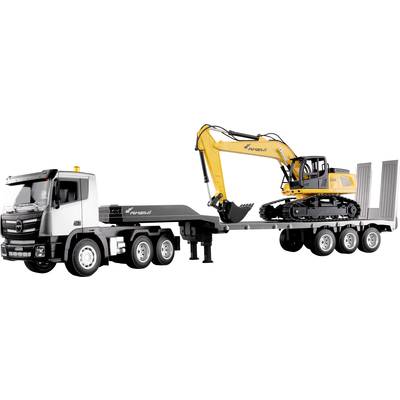Un pelleteuse jaune est posée sur une remorque de camion. Le camion est noir et argenté. Le bras de la pelleteuse est levé, prêt pour le transport.