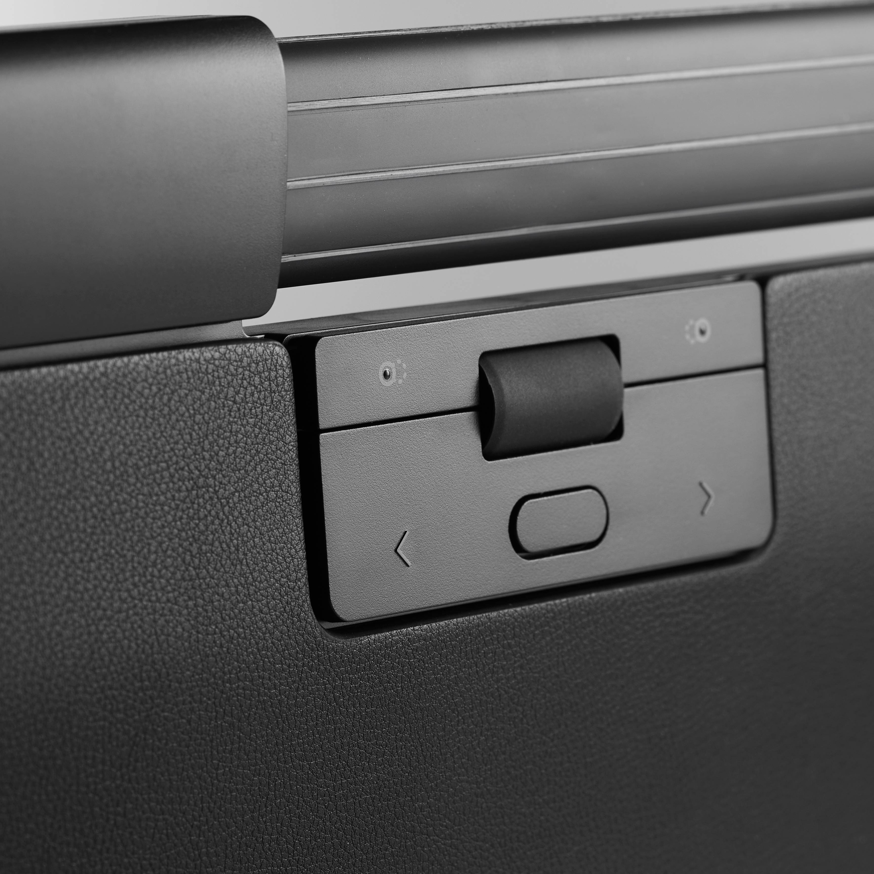 Surface texturée noire avec un panneau de commande rectangulaire présentant deux touches fléchées et une touche centrale.