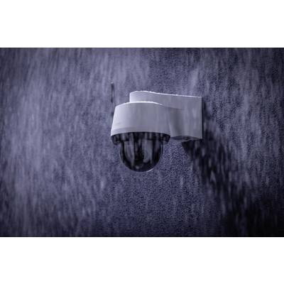 Caméra de surveillance montée sur un mur sous la pluie.