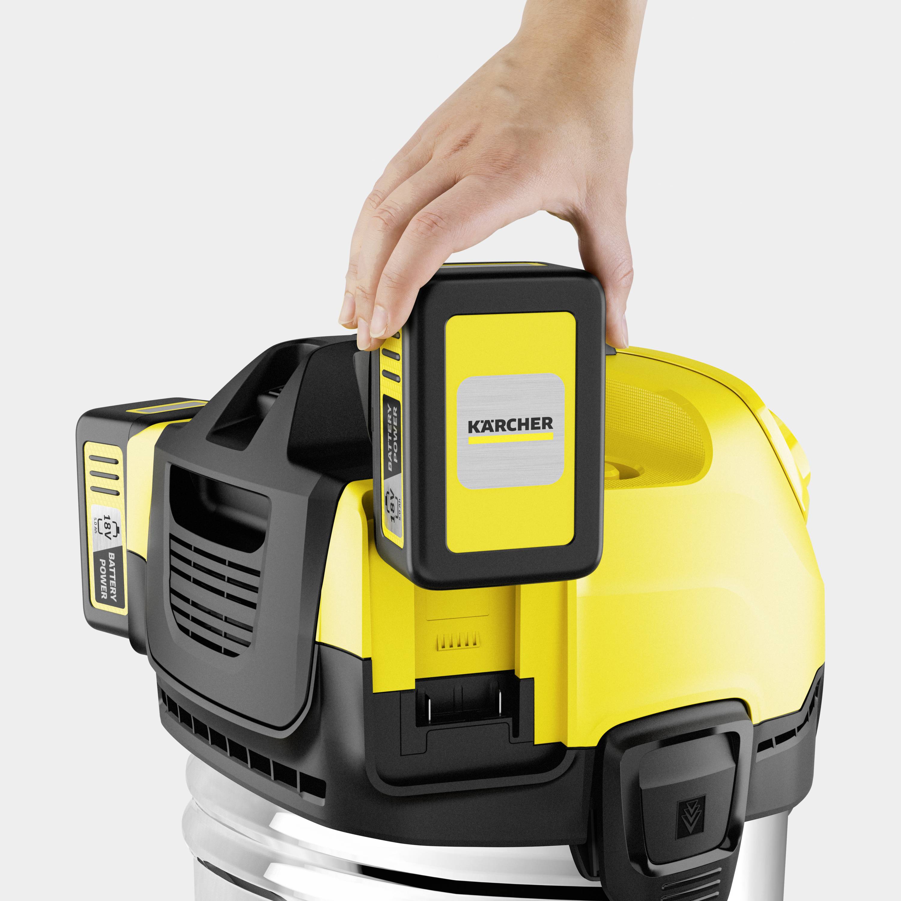 Une main saisit la poignée d'un aspirateur Kärcher jaune et noir. Le focus est mis sur le module de commande situé sur le dessus de l'appareil.
