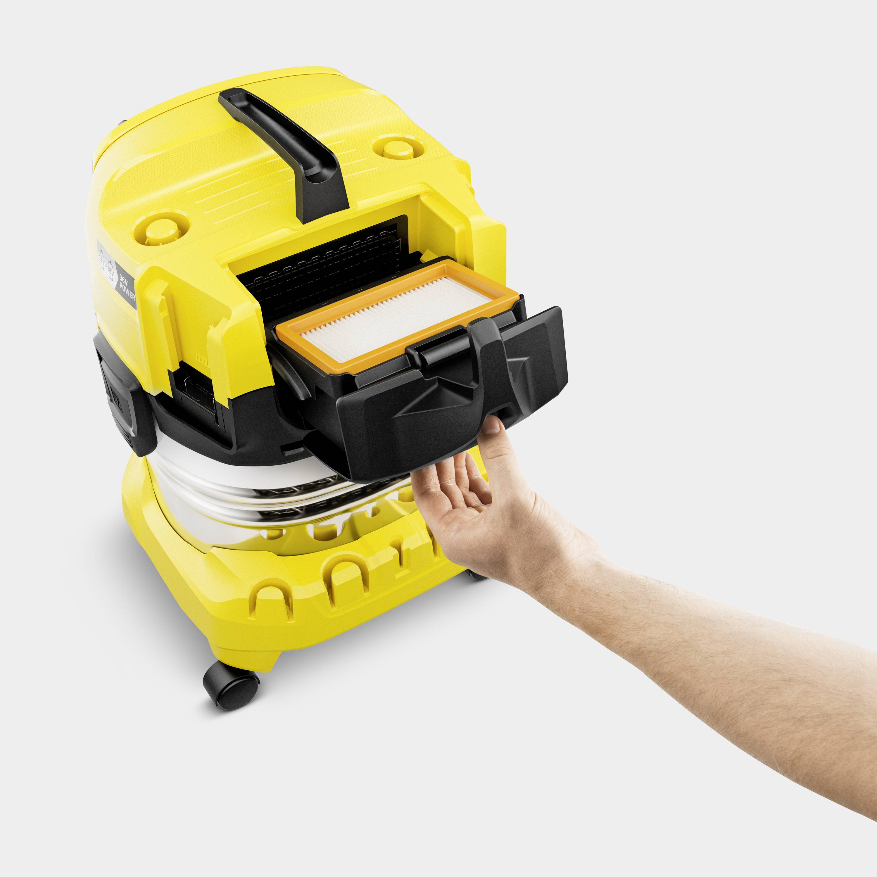 Une main sort le réservoir à poussière d'un aspirateur jaune pour montrer le filtre.