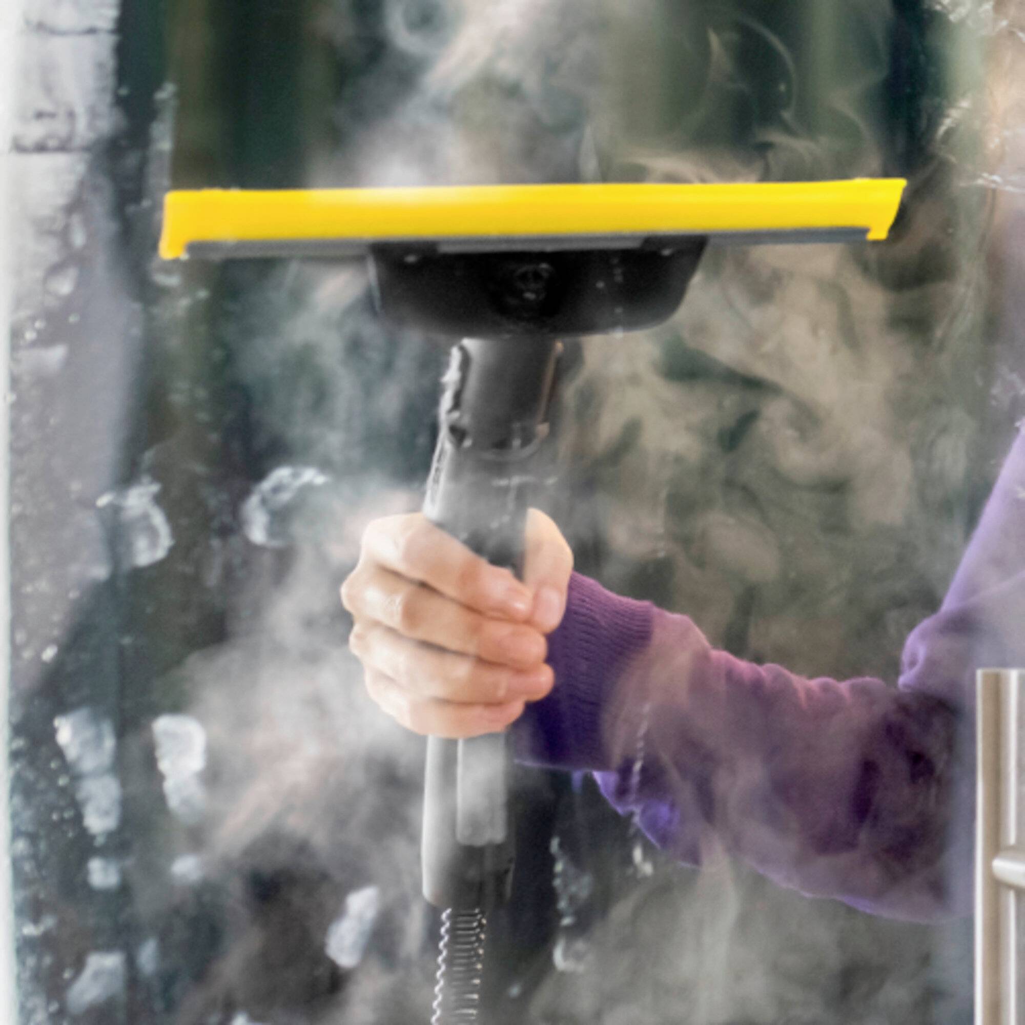 Une personne utilisant un nettoyeur vapeur pour éliminer des taches ou nettoyer une surface. L'appareil émet de la vapeur visible, indiquant un nettoyage en cours.