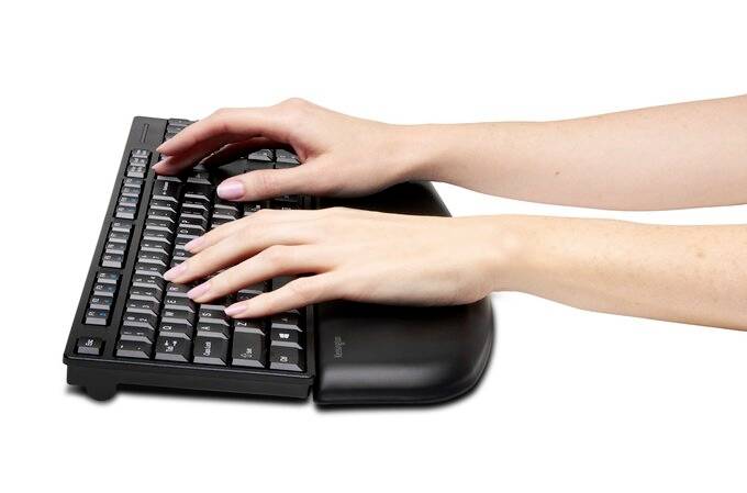 Des mains tapent sur un clavier noir avec un repose-poignets.