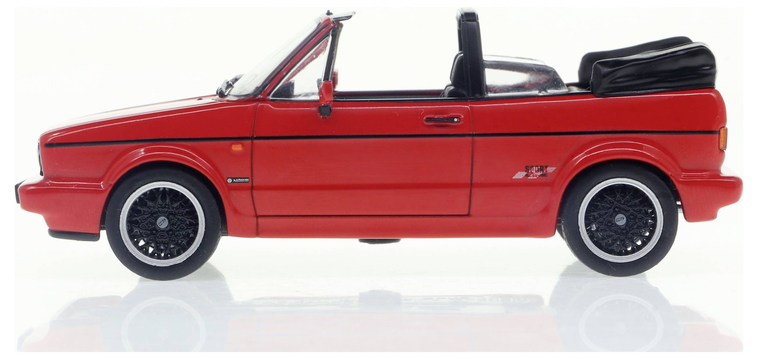Une voiture miniature cabriolet rouge avec capote ouverte, jantes noires, photographiée de profil sur un fond blanc.