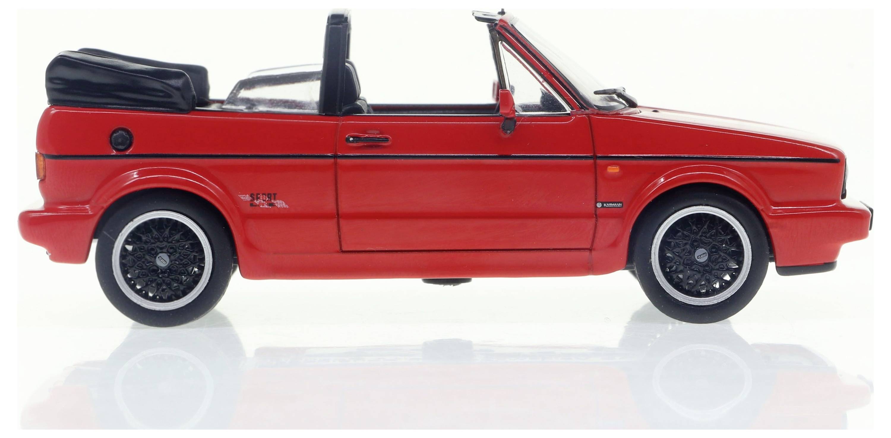 Voiture cabriolet rouge, vue de côté, avec capote rabattue et jantes noires, sur fond blanc.