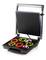 Un grill ouvert avec des anneaux colorés de légumes et de fruits sur la surface de cuisson.