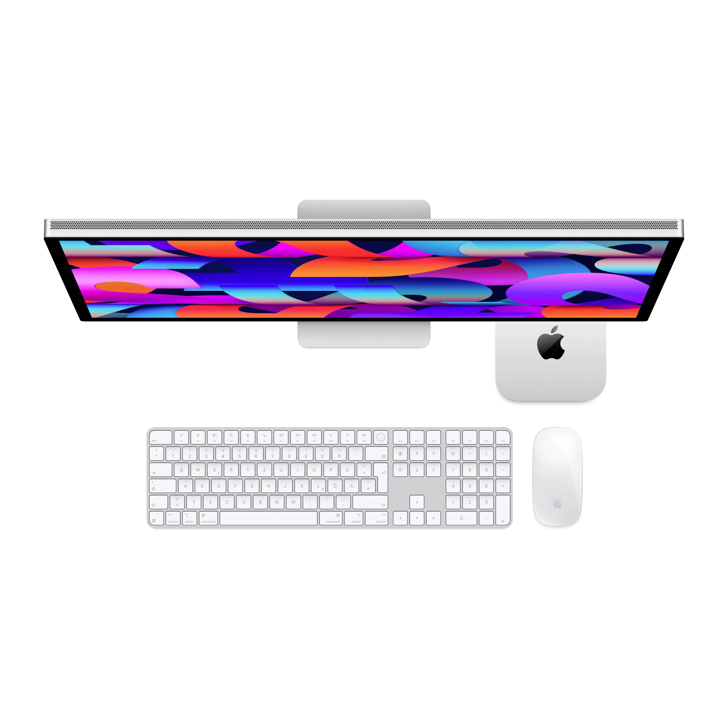 Vue de dessus d'un bureau avec un clavier, une souris et un écran affichant un fond d'écran aux motifs colorés. Logo Apple sur l'unité centrale.