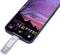 Un téléphone portable affiche une photo d'un crépuscule pittoresque avec un ciel lilas et rose. Une clé USB est connectée au téléphone.
