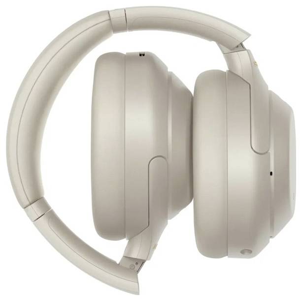 Une paire d'écouteurs sans fil over-ear beige, vus de côté, repliés pour un rangement portable.