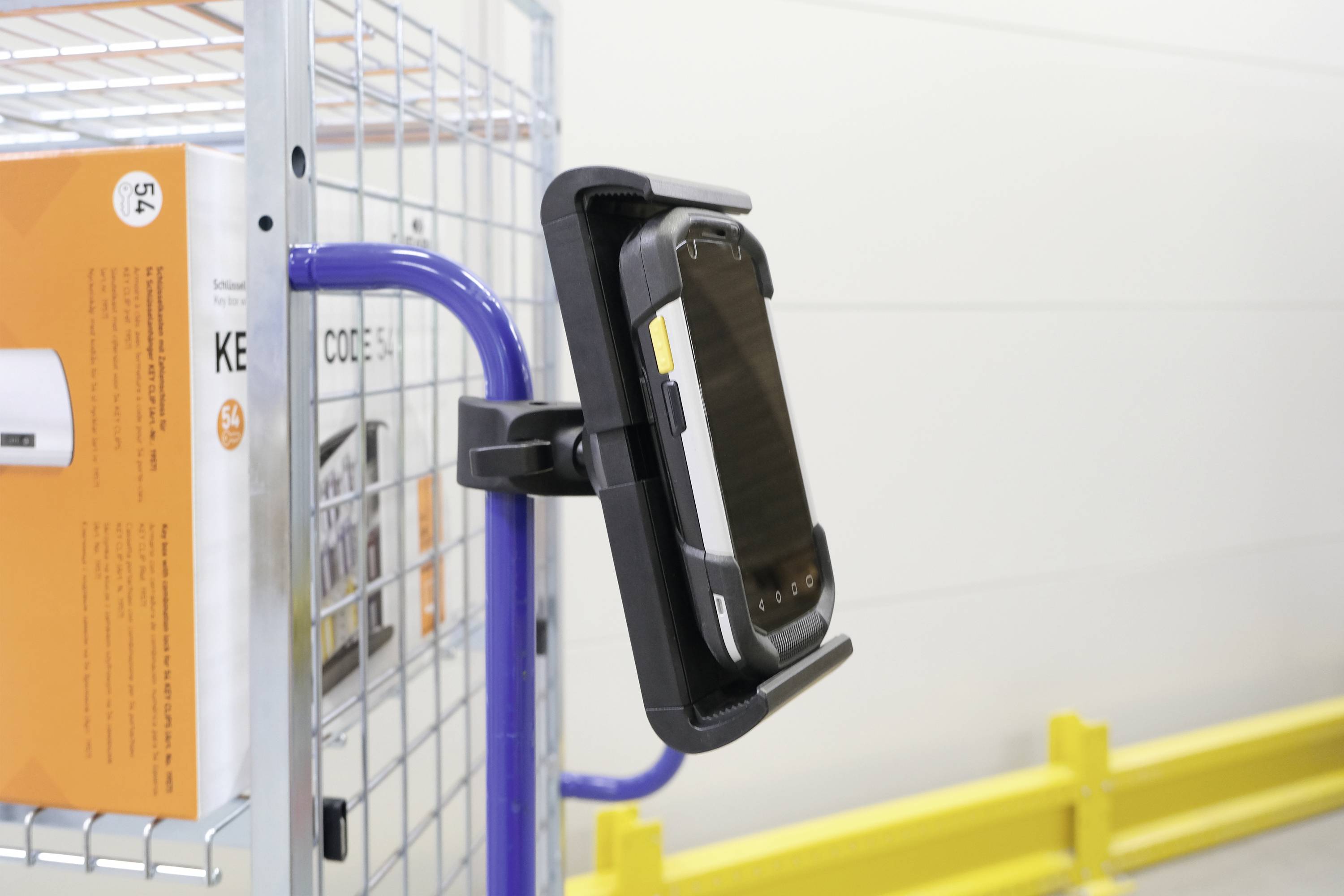 Tablette dans un support sur un chariot de supermarché dans un entrepôt. Affiche un processus logistique technique. Côté droit du chariot avec un carton.