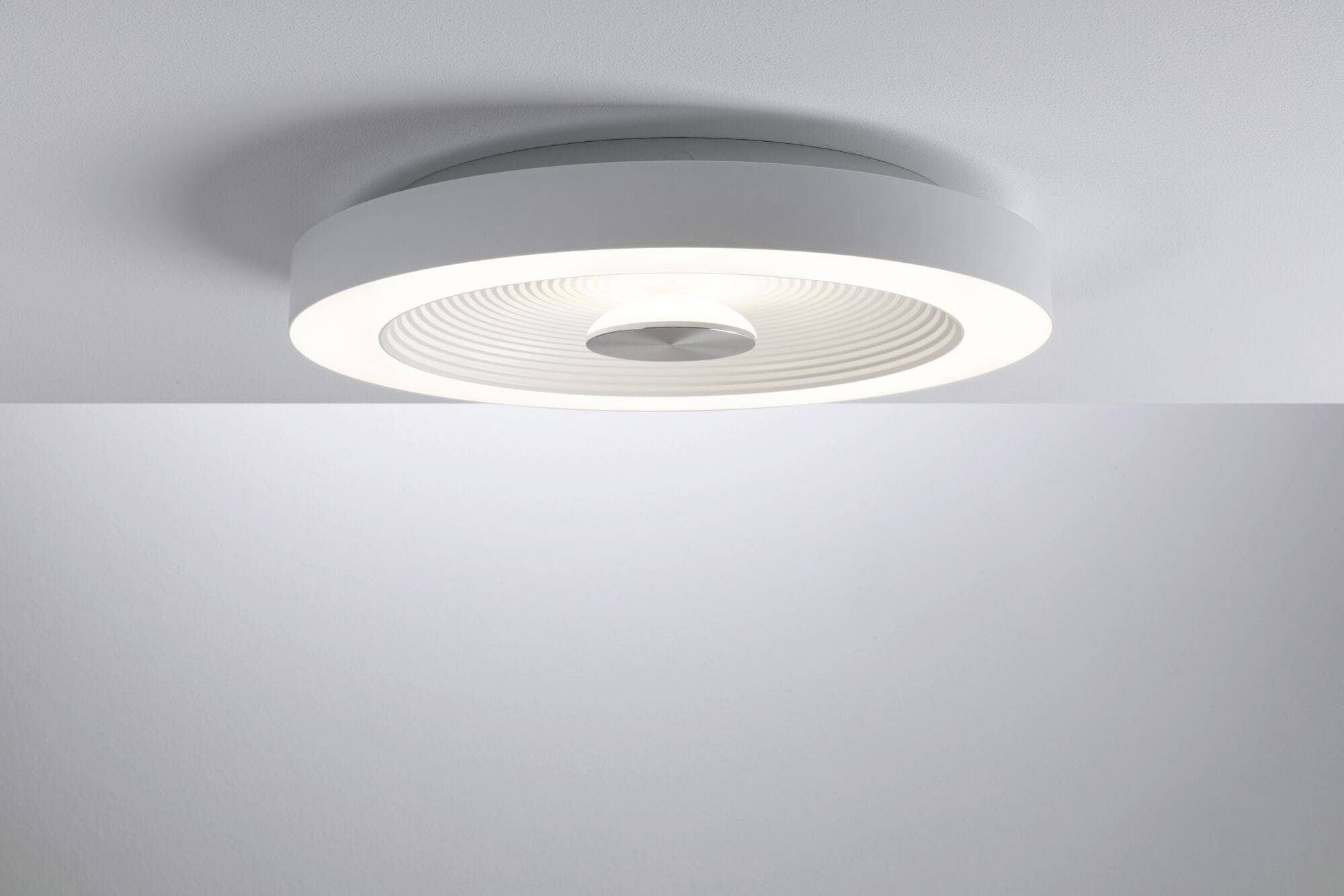 Luminaire plafonnier rond au design moderne et minimaliste, fixé de manière permanente à un plafond gris clair. Éclaire uniformément vers le bas.