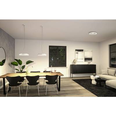 Salle à manger avec une table en bois et six chaises devant un mur de fenêtres. Des plantes à gauche, un canapé à droite. Éclairage doux. Design moderne.