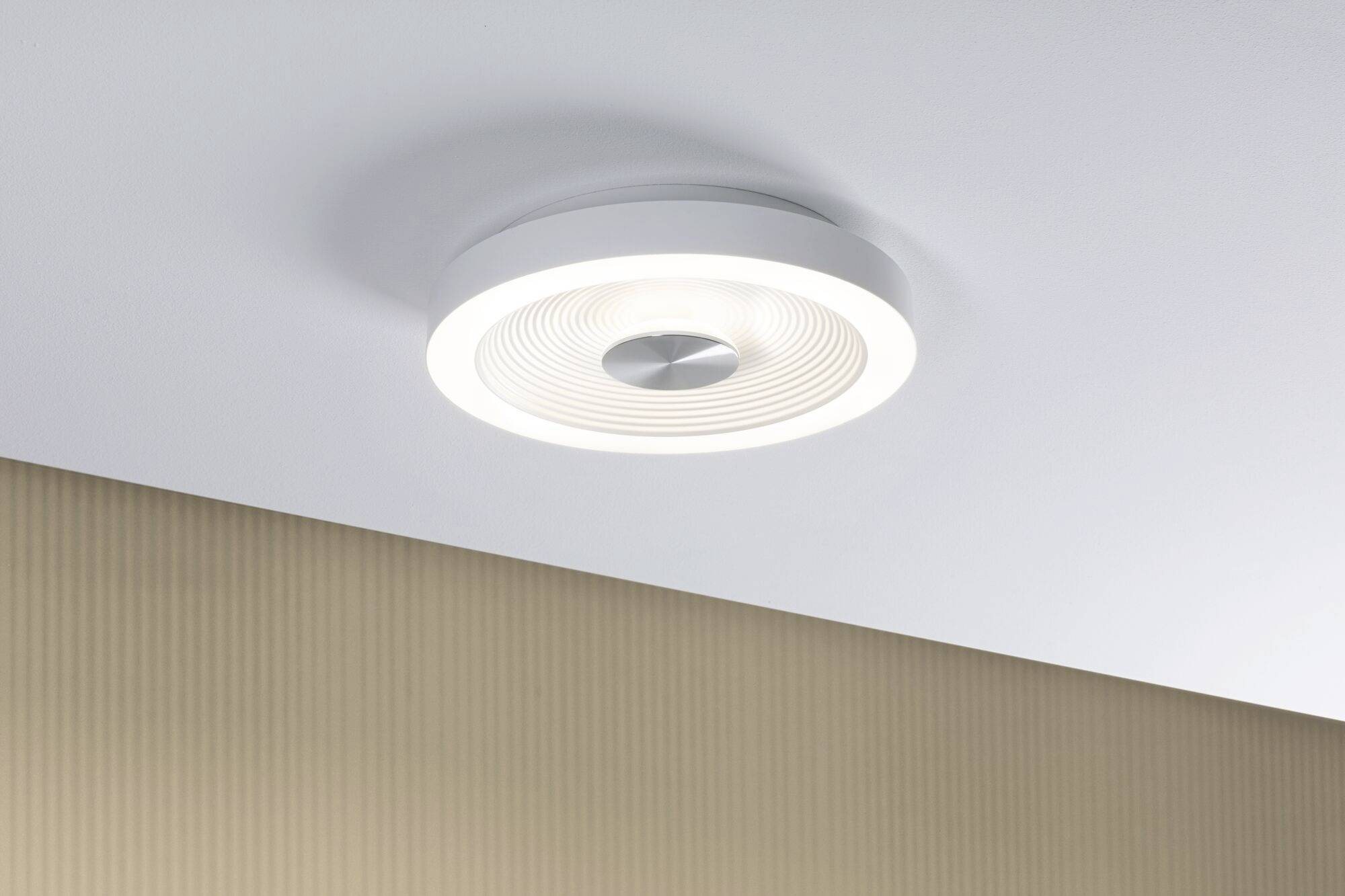 Plafonnier au design moderne et rond, diffusant une lumière blanche agréable. Lampe installée sur un plafond blanc avec un arrière-plan beige texturé.
