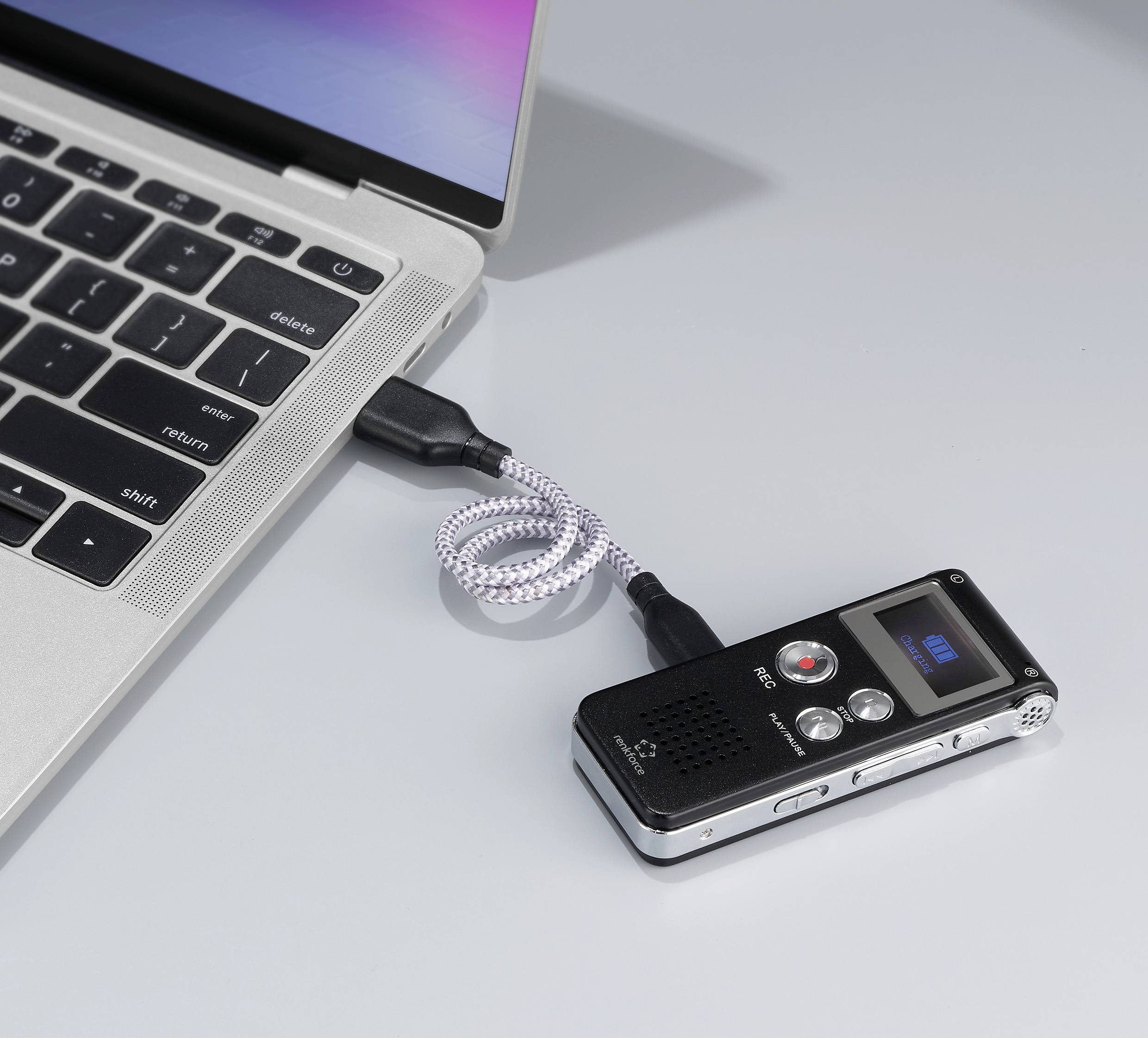 Un dictaphone est connecté à un ordinateur portable via un câble USB. L'écran du dictaphone affiche '001'.