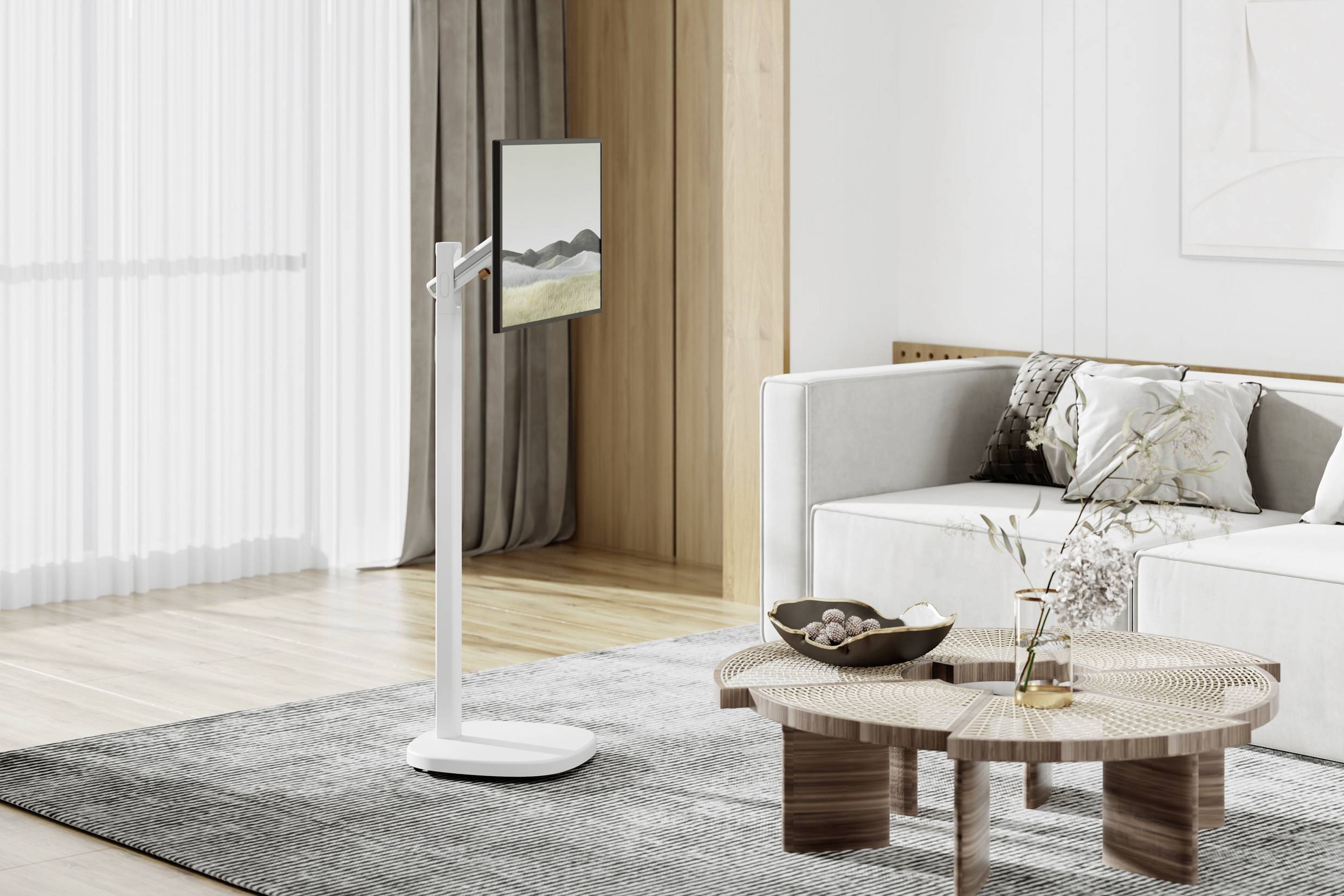 Espace de vie moderne et minimaliste avec moquette grise, table basse en bois et canapé clair. Écran plat sur support vertical à gauche.