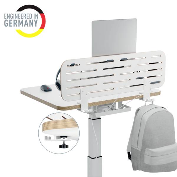 Un bureau réglable en hauteur avec un ordinateur portable et un sac à dos gris, le logo 'Engineered in Germany' en haut à gauche.