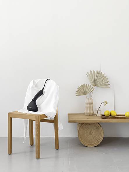 Un espace minimaliste avec un tabouret en bois et un banc en bois à côté d'un mur blanc. Sur le banc, des vases et des citrons sont disposés.