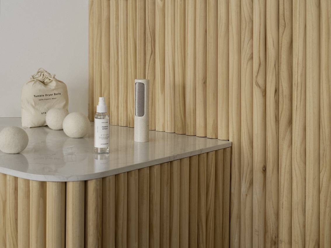 Espace revêtu de bois avec un plateau en marbre ; sur celui-ci, deux bouteilles et un sac en tissu. Style décoratif minimaliste.