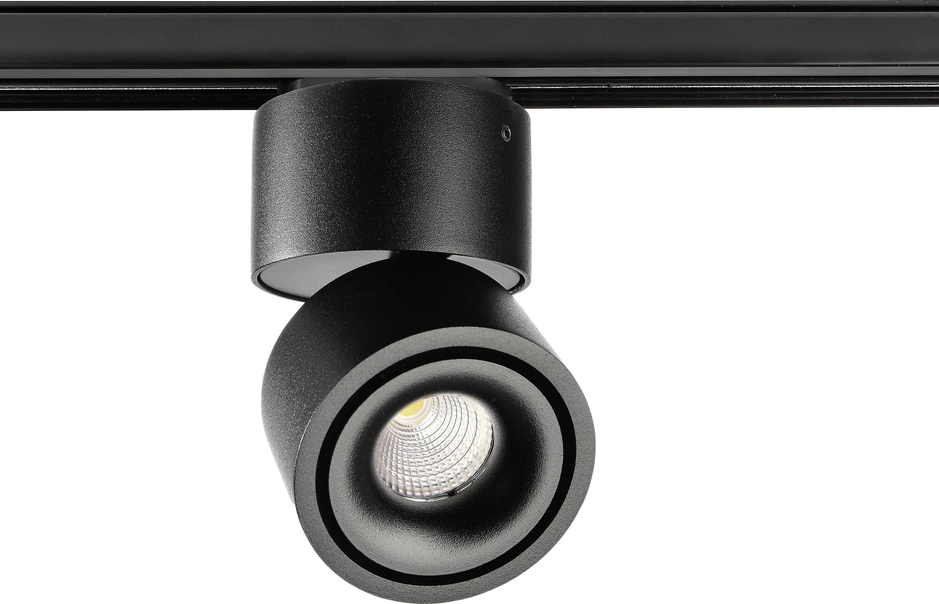 Projecteur LED noir pivotant monté sur rail, projetant une lumière vers le bas dans un design moderne et minimaliste.