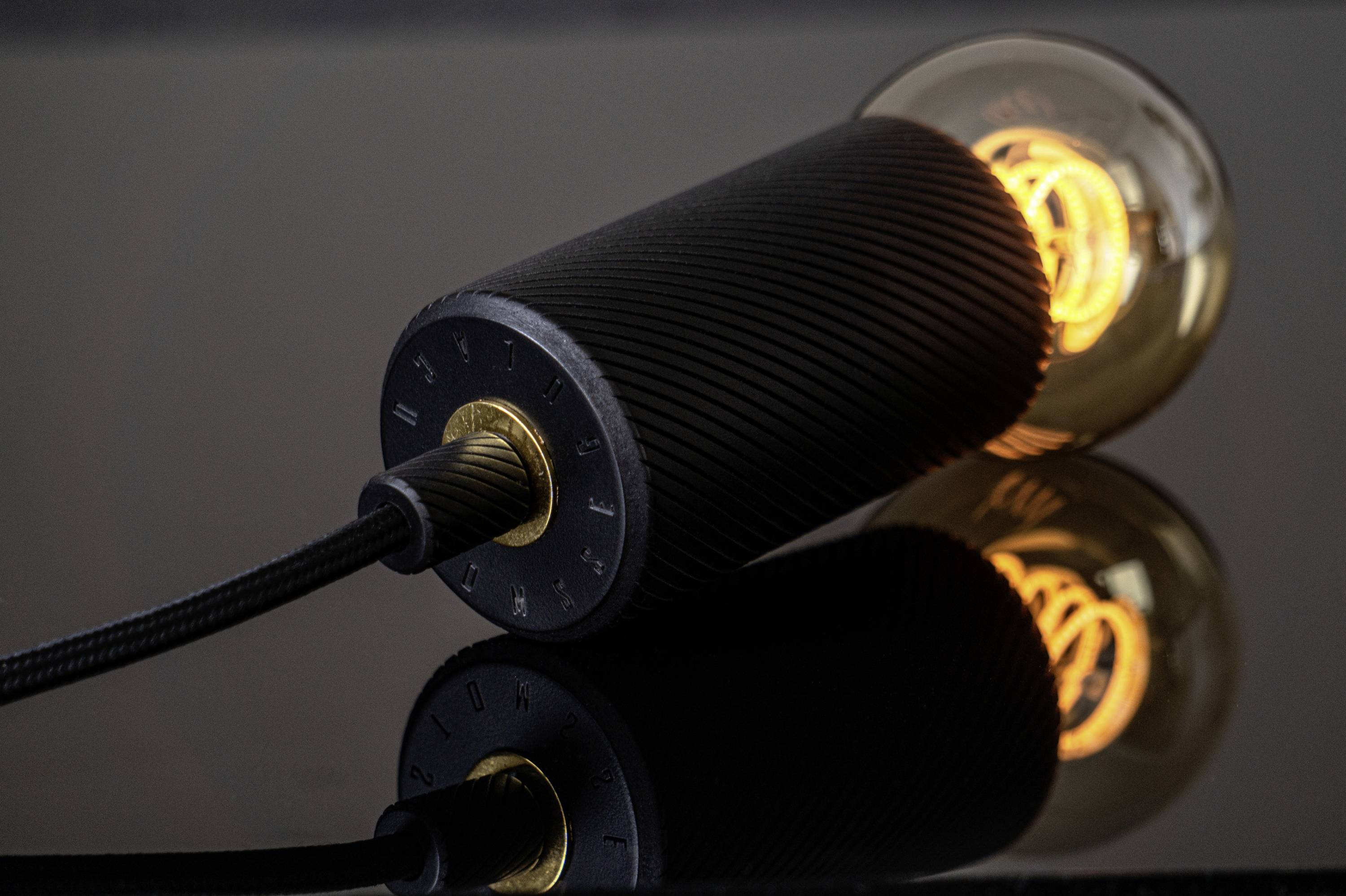 Gros plan sur une ampoule LED moderne et lumineuse, posée sur une surface réfléchissante. La spirale à l'intérieur de l'ampoule brille intensément.