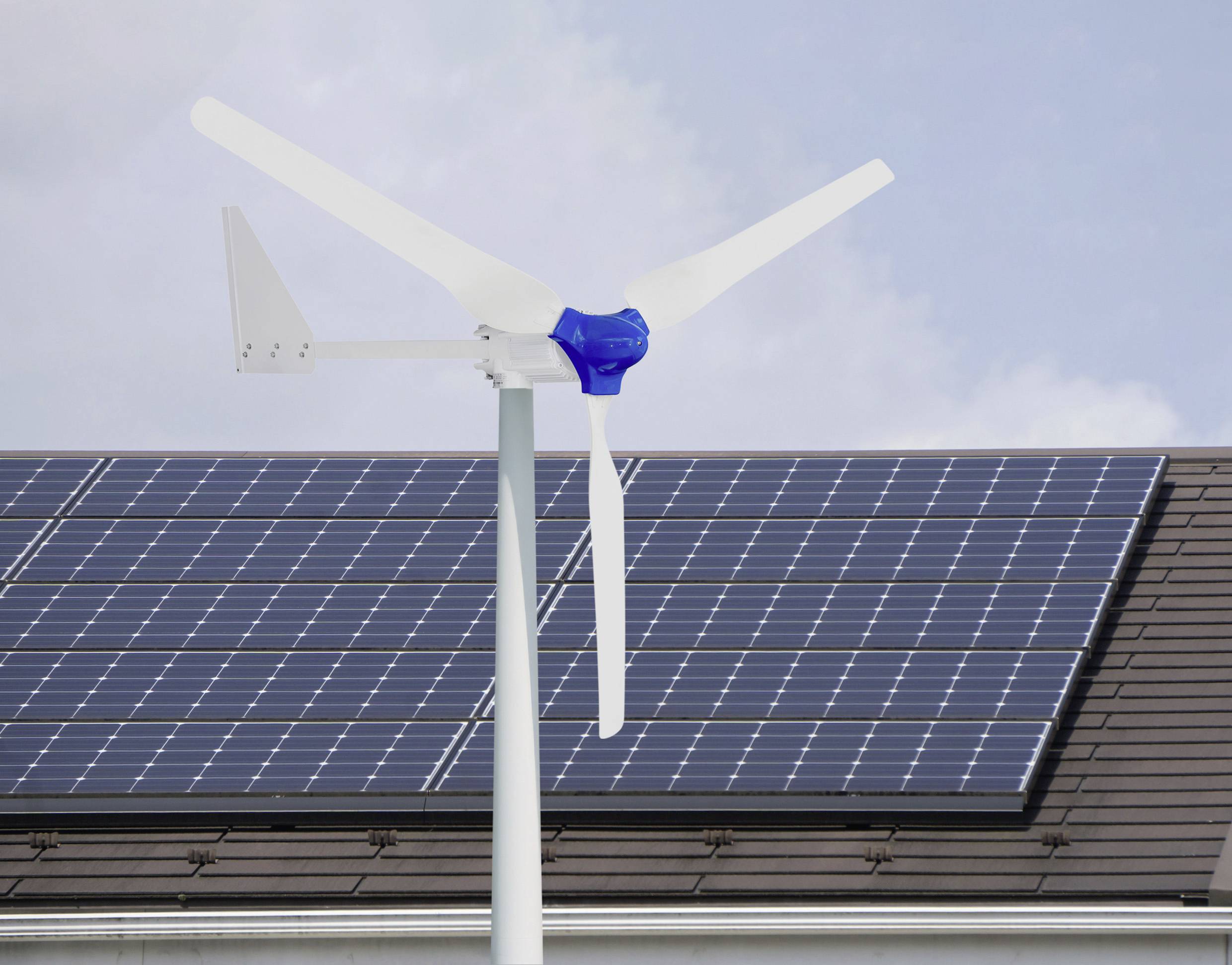 Une éolienne à trois pales devant un toit couvert de panneaux solaires symbolise les sources d'énergie renouvelables.