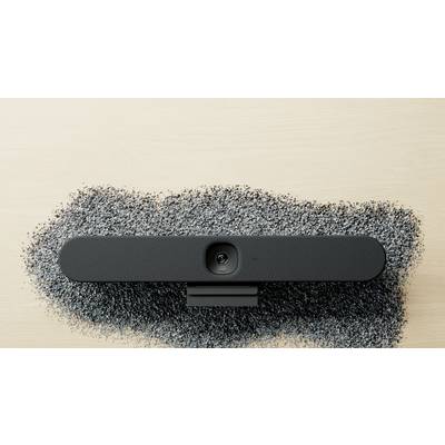Haut-parleur noir oval sur une table claire, entouré de particules sombres et dispersées de petite taille.