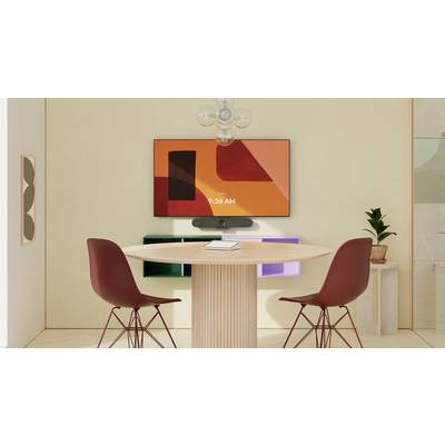 Table ronde avec deux chaises rouges dans un espace moderne, téléviseur contre un mur beige, plante artificielle à droite, design contemporain et minimaliste.
