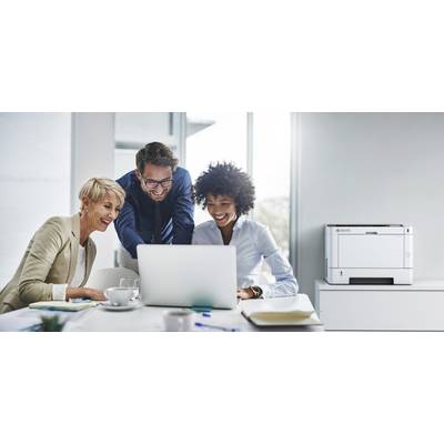 Trois personnes sourient et travaillent ensemble sur un ordinateur portable dans un bureau lumineux, avec une imprimante posée sur une table à l'arrière-plan.