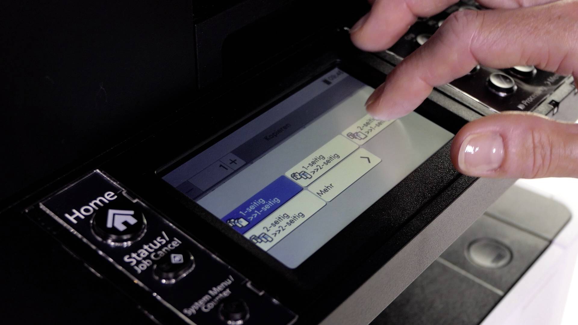 Une main manipule le panneau de commande tactile d'une imprimante, affichant les paramètres d'impression.