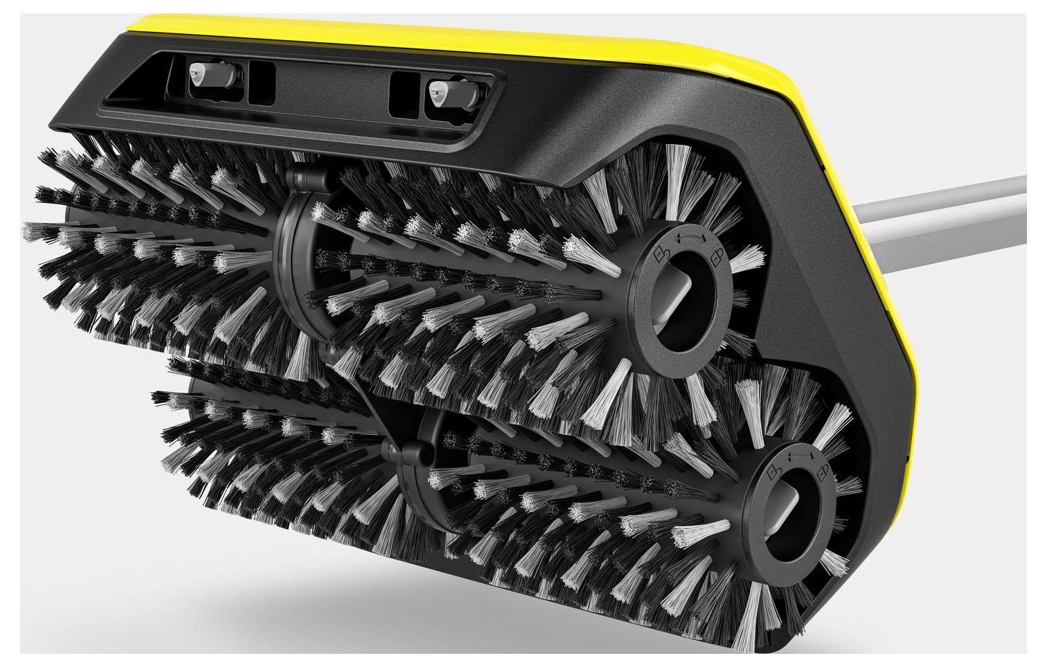 Gros plan sur une brosse noire avec des touches jaunes, comportant deux rouleaux rotatifs garnis de poils.