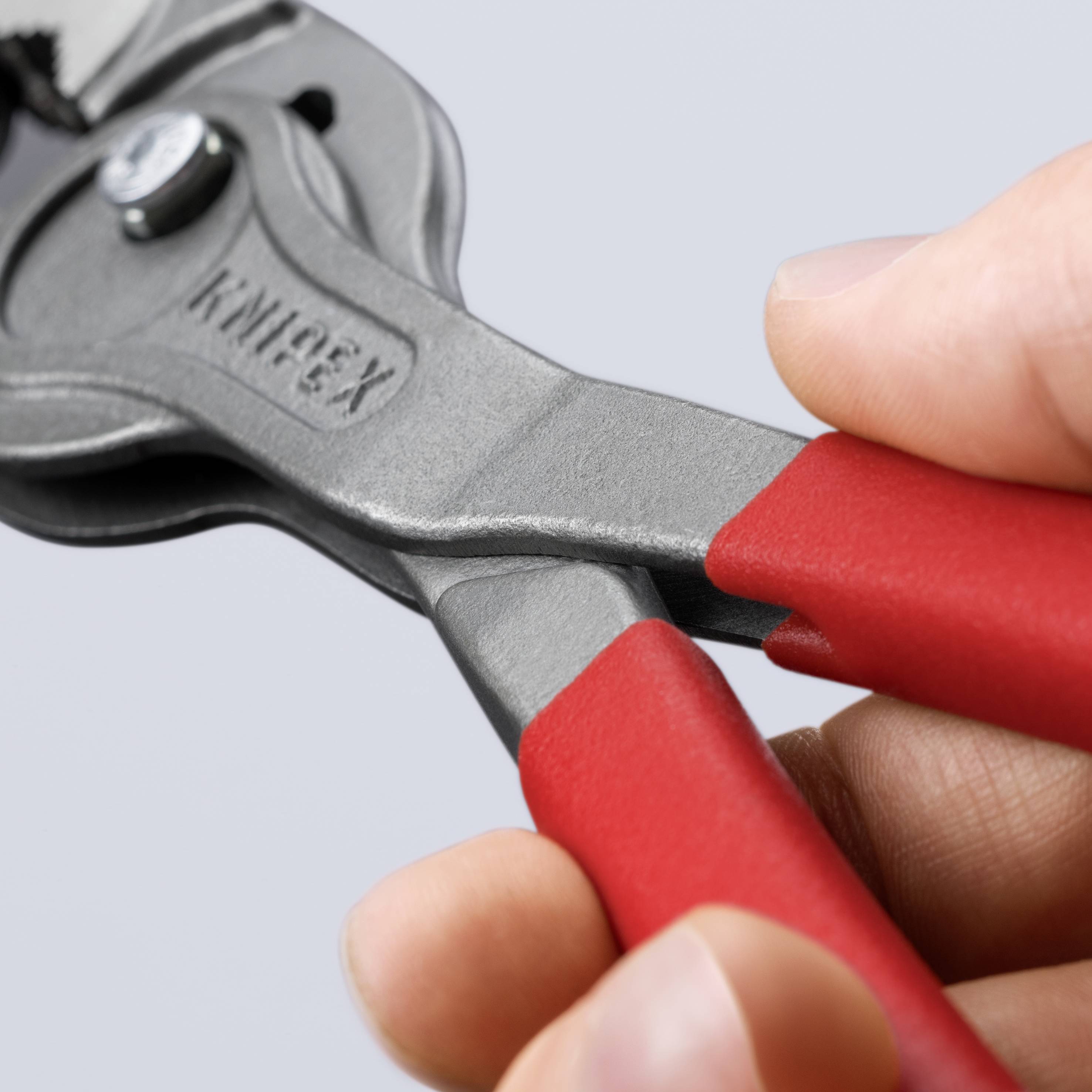 Une main tient une pince réglable à poignée rouge, utilisée pour saisir et tourner des objets.
