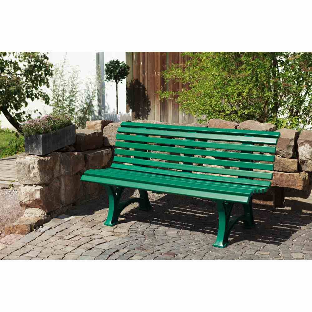 Banc vert dans un chemin pavé, entouré de pierres et de plantes dans un espace jardin.