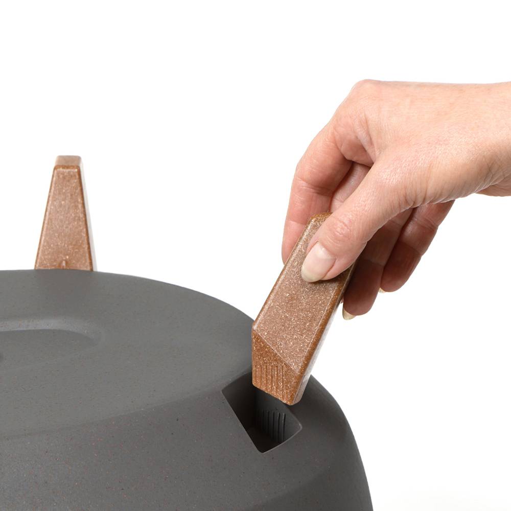 Une main positionne une pièce en forme de coin sur un objet. La pièce semble s'adapter à un support.