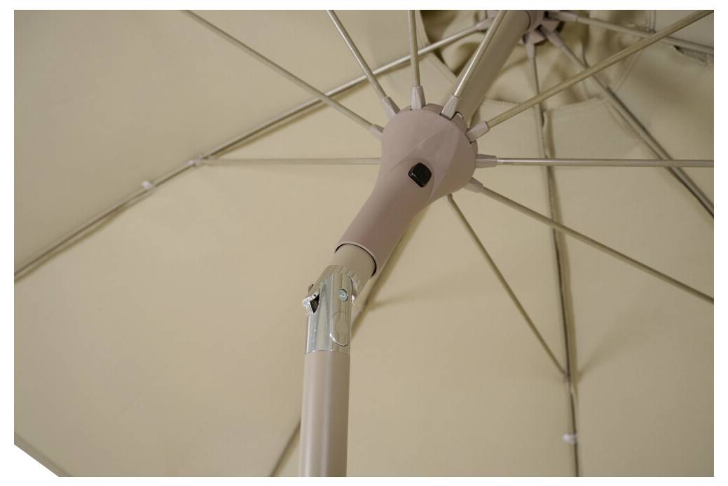 Parasol beige, vu du dessous. Les branches métalliques et le mât central forment la structure.