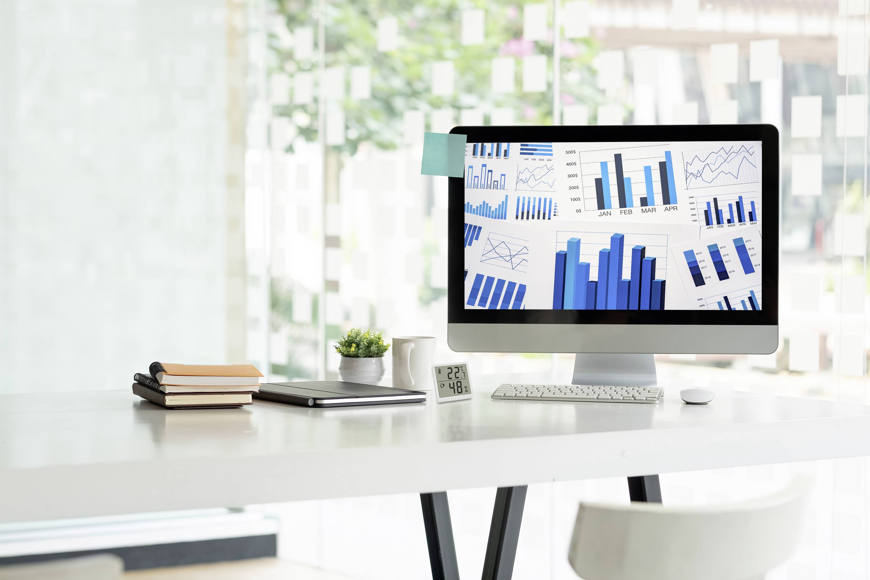 Un écran d'ordinateur affiche différents graphiques à barres et à lignes présentant des analyses de données. Le bureau est conçu de manière minimaliste.