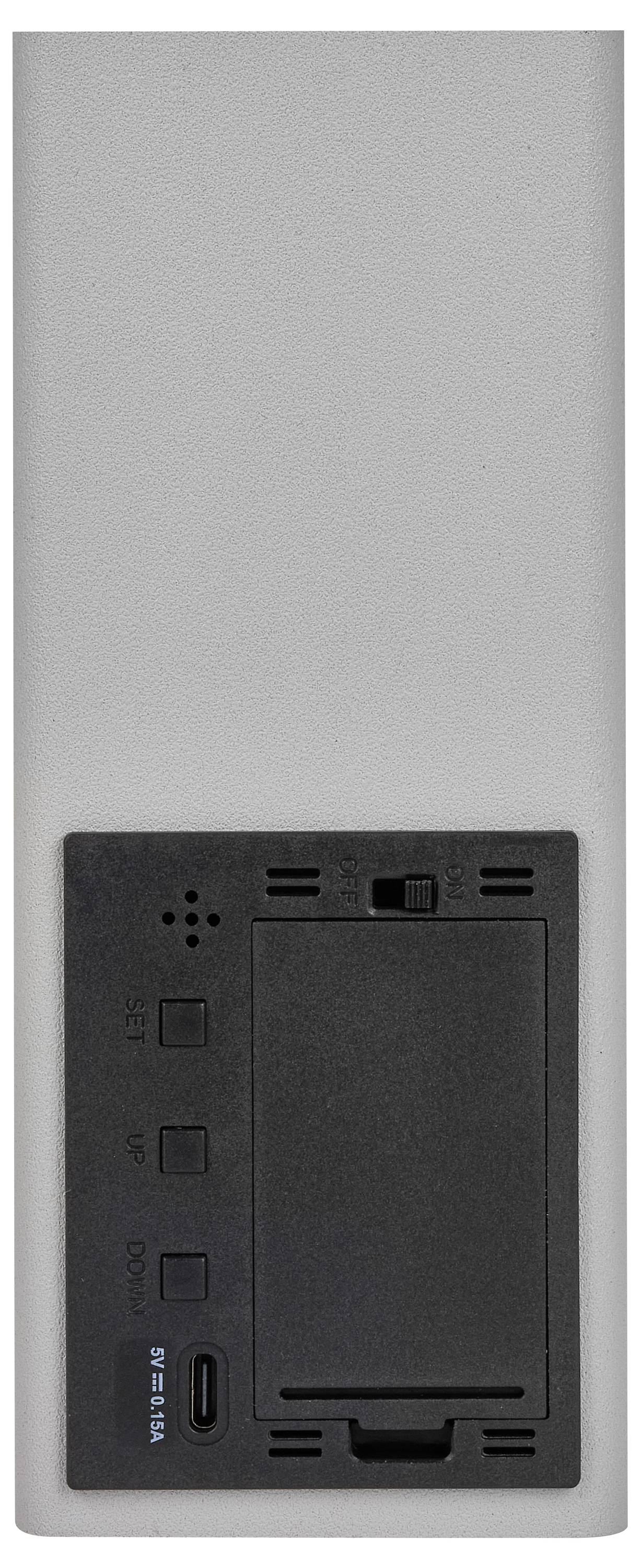 Un appareil gris rectangulaire avec un panneau de commande noir montrant des touches. Face inférieure équipée d'un port USB-C. Probablement un dispositif technique ou un chargeur.